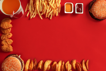 Fast food dish top view. Meat burger, potato chips and glass of drink on red background. Takeaway composition.の写真素材