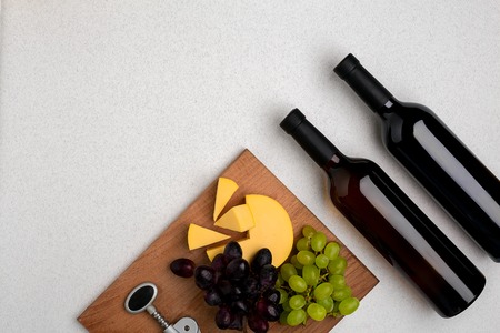 Two bottles of white and red wine, cheese and grapes. Top viewの写真素材