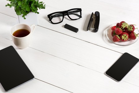 Modern workplace with digital tablet computer and mobile phone, cup of coffee and flower on white background. Top viewの写真素材