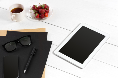 Modern workplace with digital tablet computer and mobile phone, cup of coffee, pen and empty sheet of paper.の写真素材