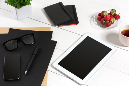 Modern workplace with digital tablet computer and mobile phone, cup of coffee, pen and empty sheet of paper.の写真素材