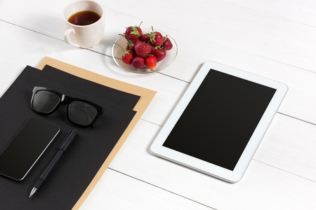 Modern workplace with digital tablet computer and mobile phone, cup of coffee, pen and empty sheet of paper.の写真素材