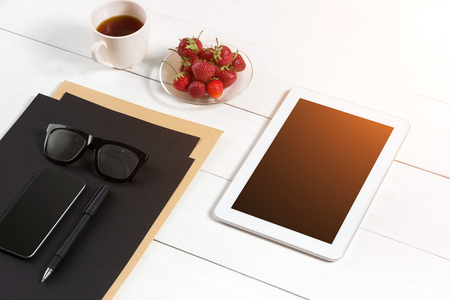 Modern workplace with digital tablet computer and mobile phone, cup of coffee, pen and empty sheet of paper.の写真素材