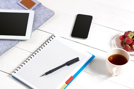 Stylish minimalistic workplace with tablet and notebook and glasses in flat lay style. White background.の写真素材