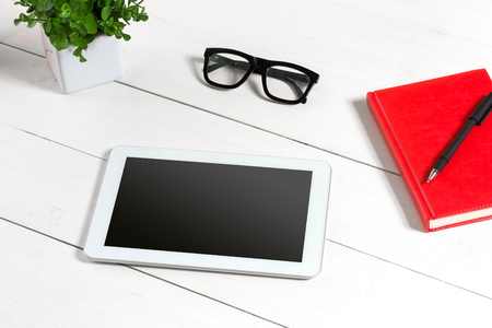 Stylish minimalistic workplace with tablet and notebook and glasses in flat lay style. White background.の写真素材