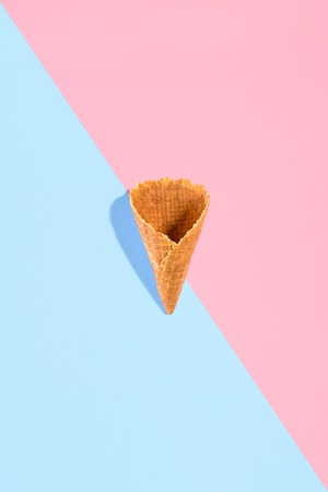 Sugar waffle cone for ice cream arranged in pattern on pink and mint background. The image with copy space can be used as a background for the design of the confectionery menuの写真素材