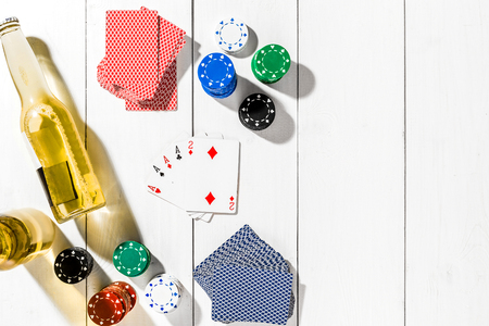 Four aces surrounded by poker chips and beer on white wooden background and copy spaceの写真素材