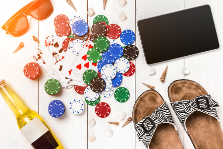 Card deck surrounded by poker chips and scattered seashells on white wooden background with copy spaceの写真素材