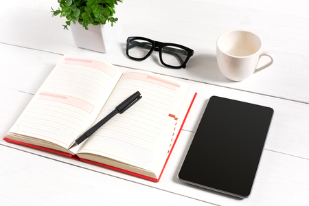 Stylish minimalistic workplace with tablet and notebook and glasses in flat lay style. White background.の写真素材