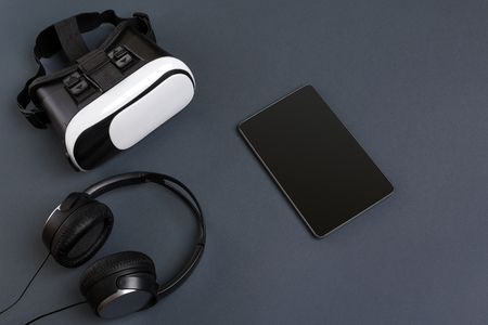 Virtual reality glasses and tablet with headphones on a gray background. Top viewの写真素材