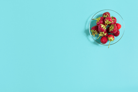 Ripe strawberries on the saucer isolated on mint background. Top view. Copy space. Still life mockup flat layの写真素材