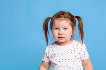 A cute little girl is smiling on a blue isolated background with pig tails for a happiness or childhood concept.の写真素材