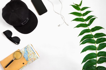 Travel accessories set on white background: smart, headphones, cap, map and sunglasses. Top view point. Flat lay. Still life. Copy spaceの写真素材