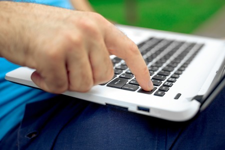 Close-up shot of handsome mans hands touching laptop computers screen.