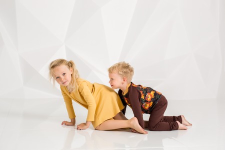 Brother and sister playing and smiling in a white studioの写真素材