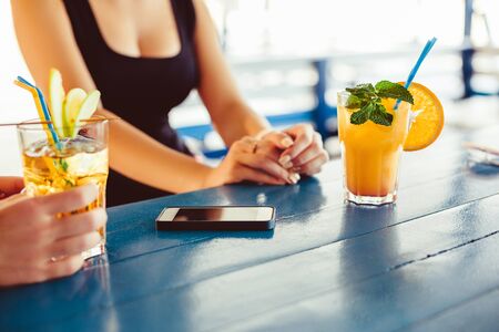Cocktail in woman hand on the open terrace in bar during summer timeの写真素材