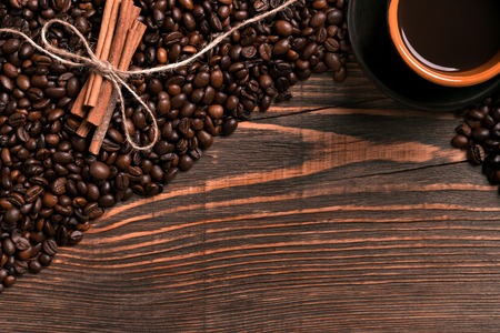 Coffee beans, cinnamon sticks and cup of brewed coffee on rusticの写真素材