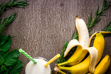 Banana smoothie and fresh banana on wooden table.の写真素材