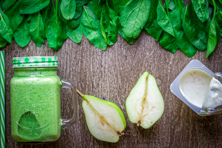 Healthy green smoothie with spinach in a mug against on wooden backgroundの写真素材