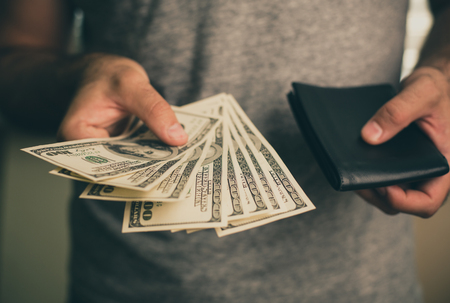A man holds dollars and black wallet in his handsの写真素材