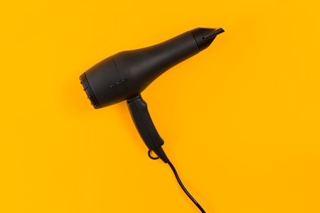 Black hair dryer on yellow paper backgroundの写真素材