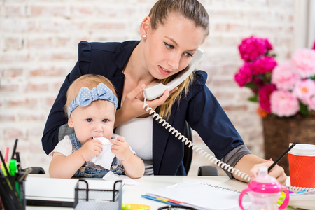 Family Business - telecommute Businesswoman and mother with kid is making a phone callの写真素材
