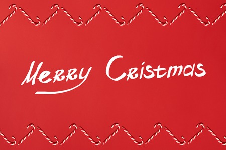 Christmas candies canes border on red background. Flat lay and top view