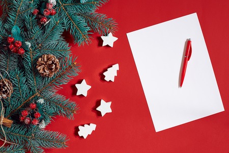 Red pen and notepad on red table decorated with a fir branch. The background for the text.の写真素材
