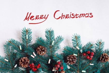 Green Christmas fir tree branches with cones isolated on white background. The inscription - Marry Christmasの写真素材
