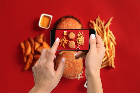 A young woman taking photo of food on smartphone, photographing meal with mobile cameraの写真素材