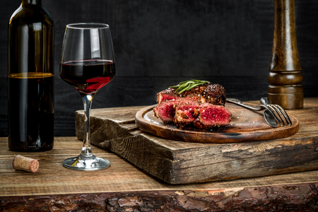 Grilled ribeye beef steak with red wine, herbs and spices on wooden tableの素材 [FY31086903672]