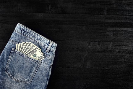 Pocket money. Dollar in hip pocket of worn blue jeans. Close-up.の写真素材
