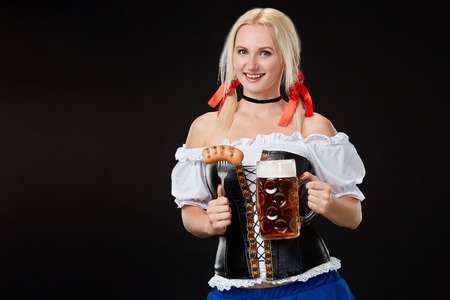Young sexy woman wearing a dirndl with beer mug on black background.の写真素材