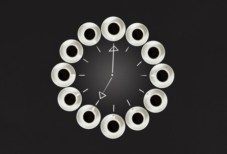 Cups with coffee, stacked in a circle. Clock consist of twenty cups. Black background. Concept time to coffeeの写真素材