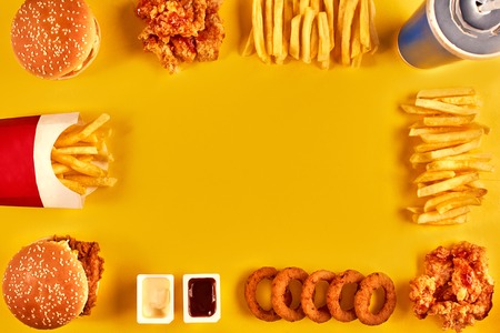 Top view hamburger, french fries and fried chicken on yellow background. Copy space for your text.の写真素材