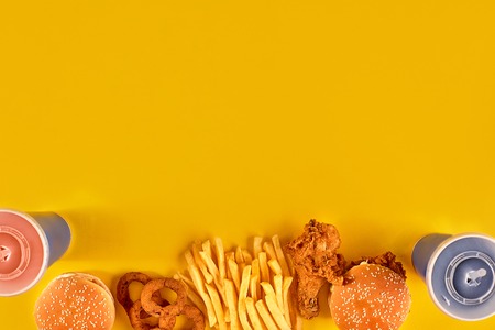 Fast food dish on yellow background. Fast food set fried chicken, meat burger and french fries. Take away fast food.の写真素材