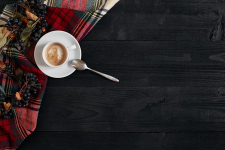 White cup of the coffee and vintage scarf on black wooden backgroundの写真素材
