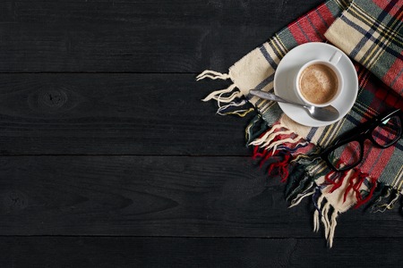 White cup of the coffee and vintage scarf on black wooden backgroundの写真素材