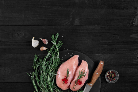 Cooking chicken breasts. On the table are spices - rosemary, red and black pepper. Concept - healthy food.の写真素材