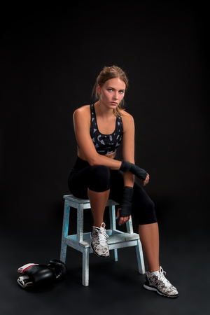 Young fit woman looking at the camera while wrapping her arms with bandage tape. Attractive girl preparing for the kickboxing training.の写真素材