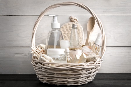 Composition of cosmetic bottles and soap in basket, on white wooden backgroundの写真素材