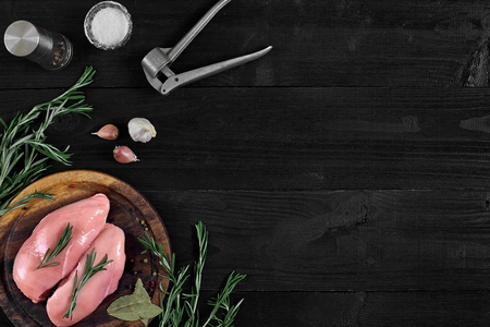 Raw chicken breast and condiments in a rustic wooden setting, top viewの写真素材