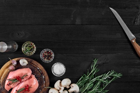 Raw chicken breast and condiments in a rustic wooden setting, top viewの写真素材