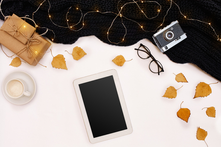 Autumn concept, dried fall leaves, mug of cocoa, old camera, scarf and tablet with blank screen. Mock upの写真素材