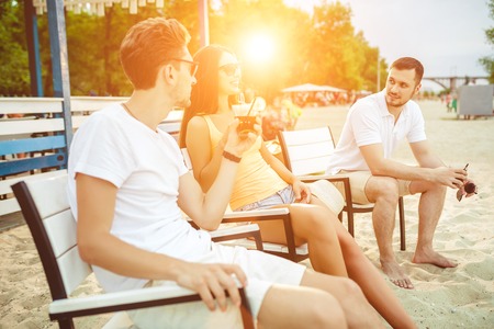 Young people enjoying summer vacation sunbathing drinking at beach bar