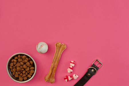 Dog snacks, dog chews, dog bone, ball toy for dog on a pink background with copy spaceの写真素材