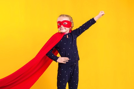 Superhero little girl in a red raincoat and a maskの写真素材