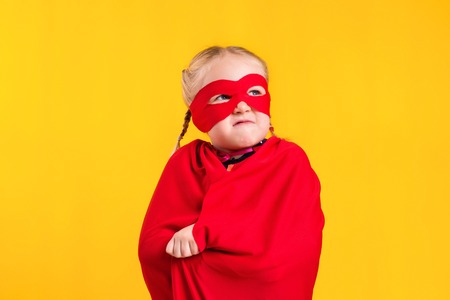 Funny little power superhero child girl in a red raincoat and a mask. Superhero concept.の写真素材