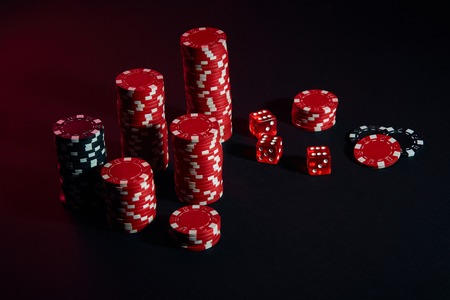 Dice and red and black chips on dark background