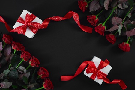 White gift boxes with red ribbon on black background. Valentines day greeting card.の写真素材